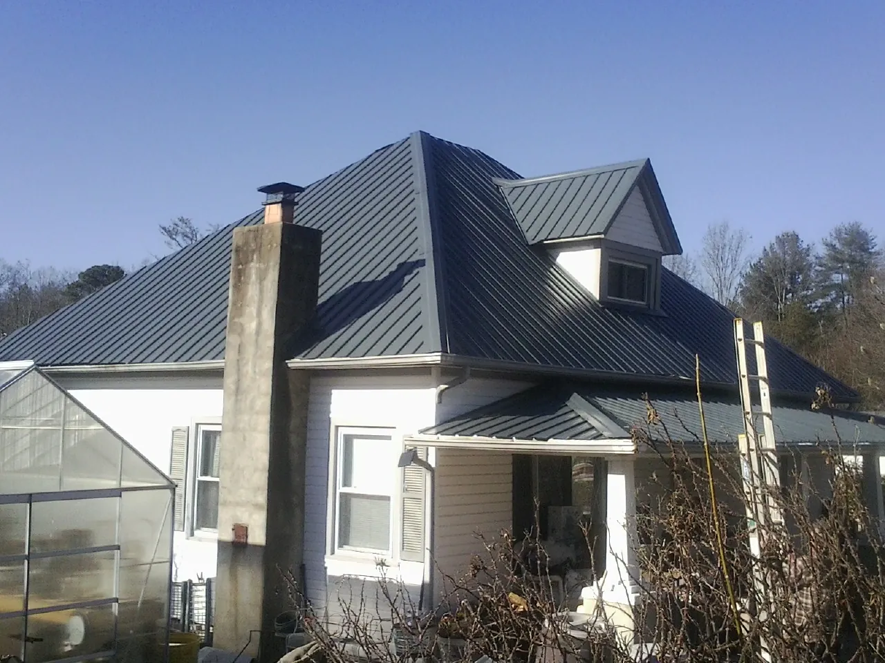 Dark blue standing seam metal roof on a white farmhouse with dormer — Slate & Tile Roof Repair by Roofing Brothers in Raeford