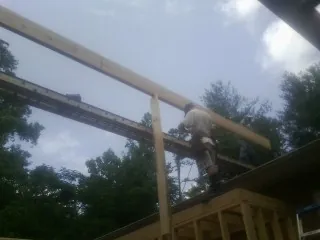Carpenter setting a ridge beam over a new addition frame — Ice Dam Removal by Roofing Brothers in Raeford