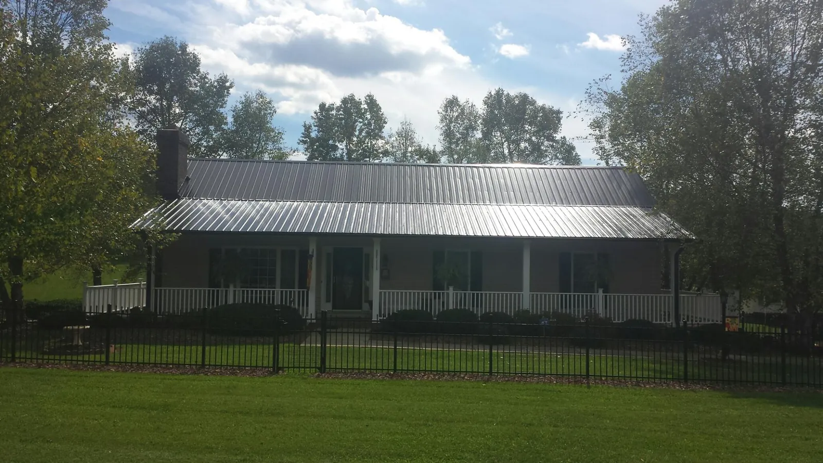 Gray metal roof on a brick ranch with a full width front porch — Gutter Guard Installation work by our crew in Raeford
