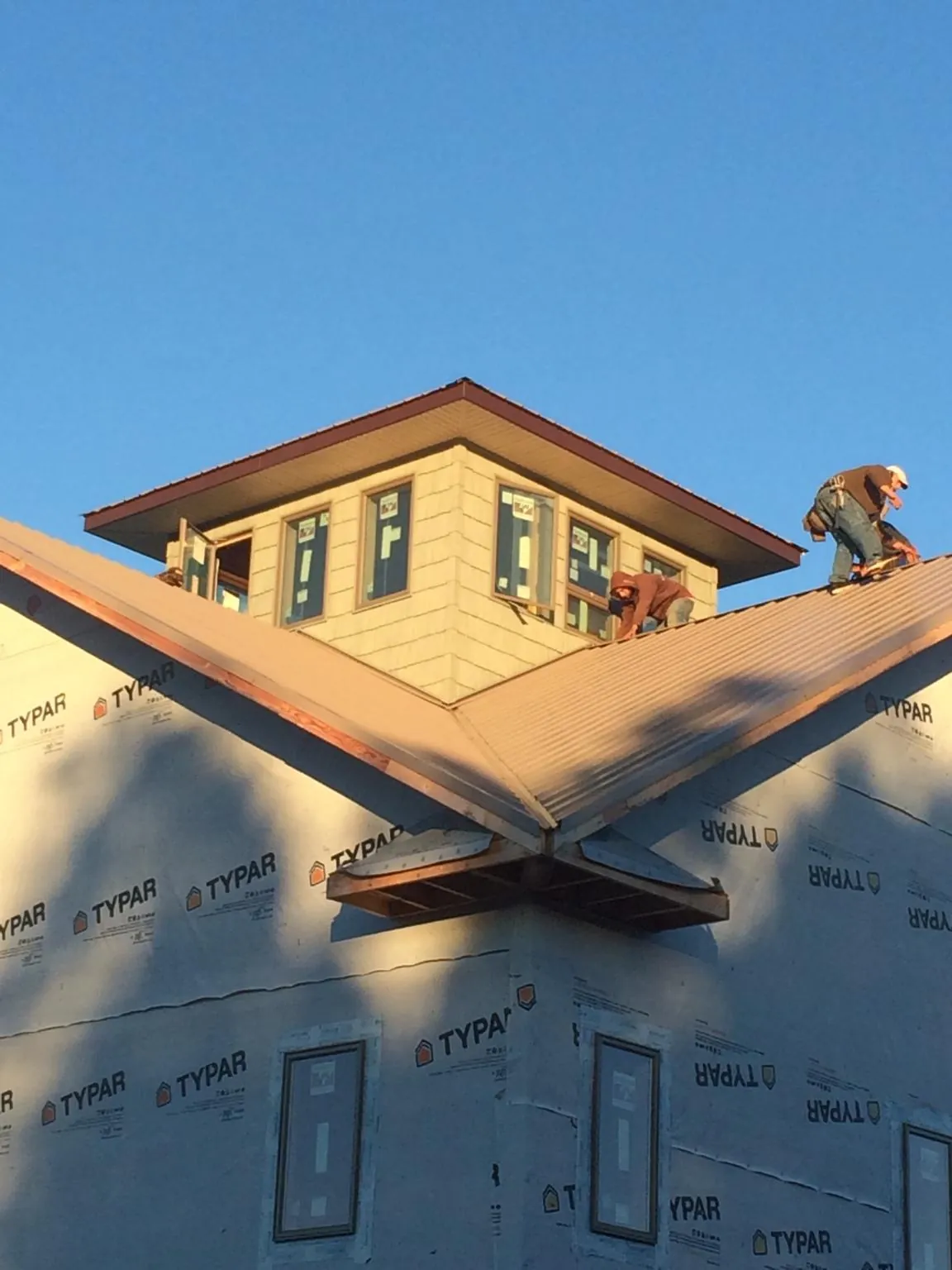 Roofers working around a rooftop cupola on a new metal roof at sunset — Roof Waterproofing in Raeford by Roofing Brothers